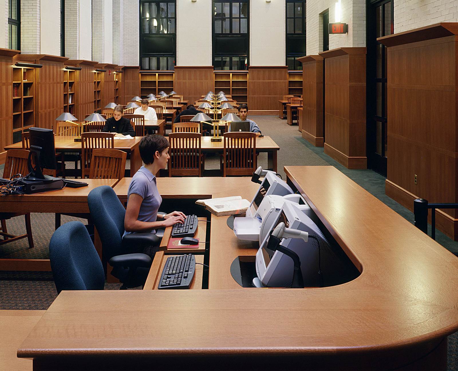 The circulation desk and the furniture in this space make for a warm and welcoming environment. Even with the high arched-glass ceilings, the warm wood keeps everything to scale.